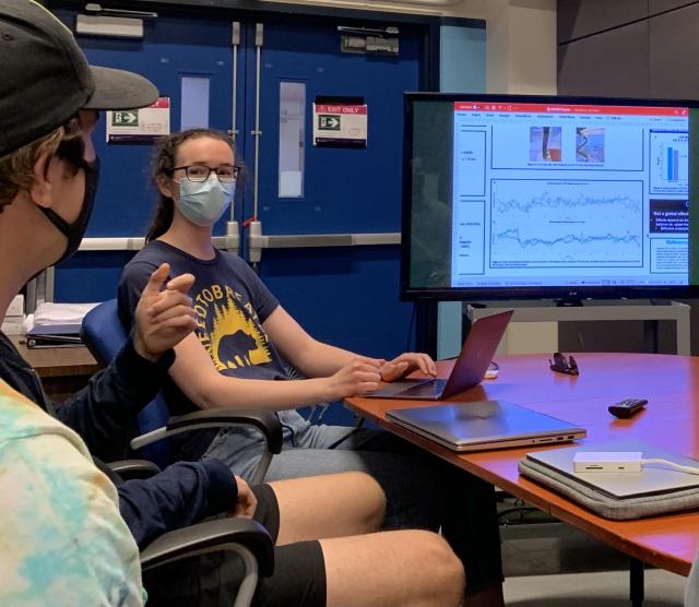 discussion around a table with a screen in the background