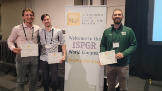 Awardees with certificates standing by a banner